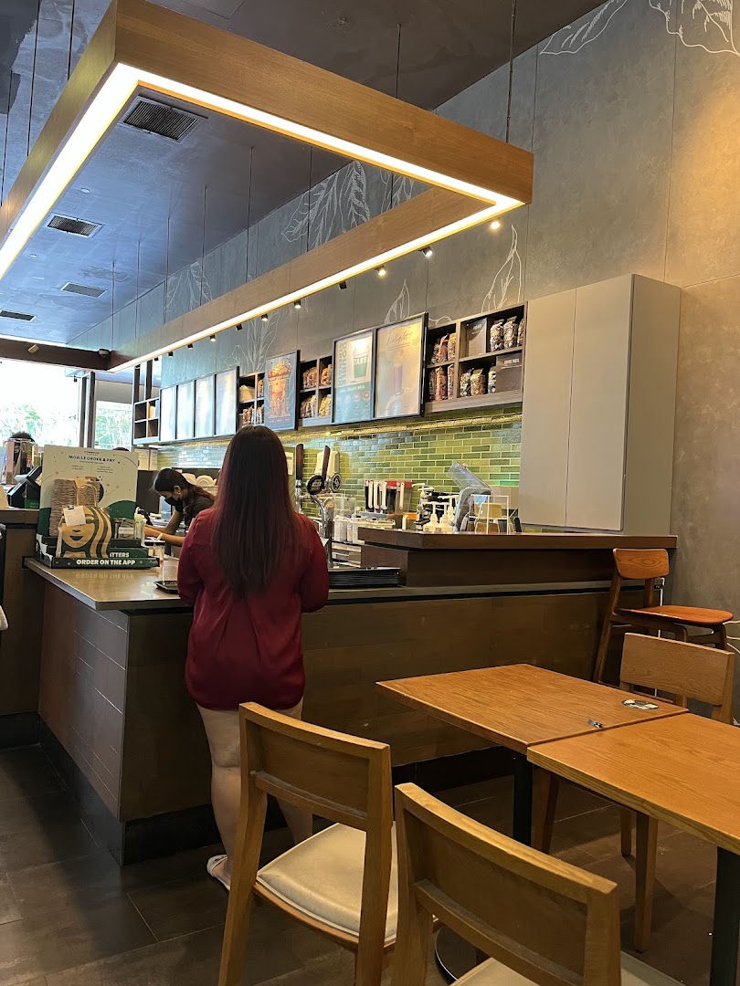 A customer orders at the counter inside Starbucks Plaza Singapura, with seating visible.
