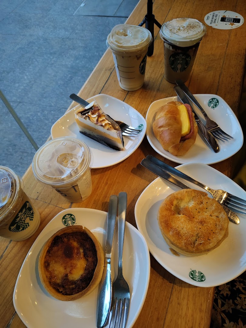 A table laden with Starbucks coffee, iced beverages, cakes, and pastries, ready to be enjoyed.