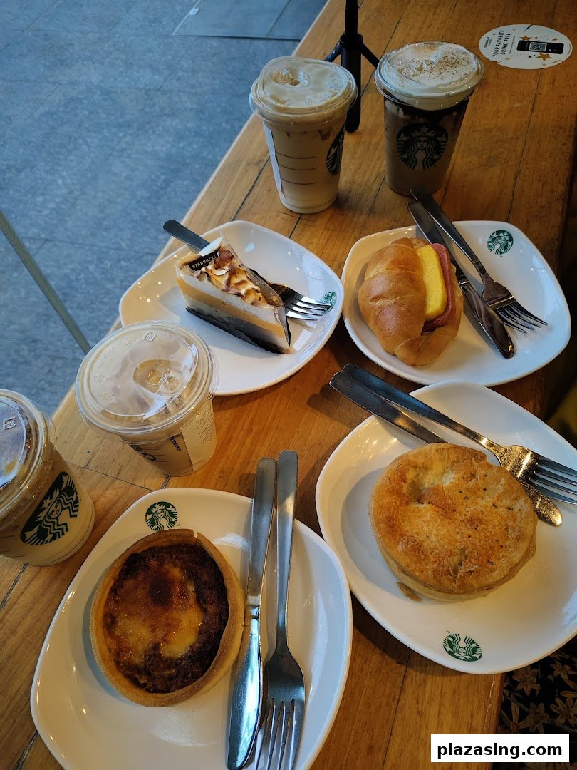 A table laden with Starbucks coffee, iced beverages, cakes, and pastries, ready to be enjoyed.