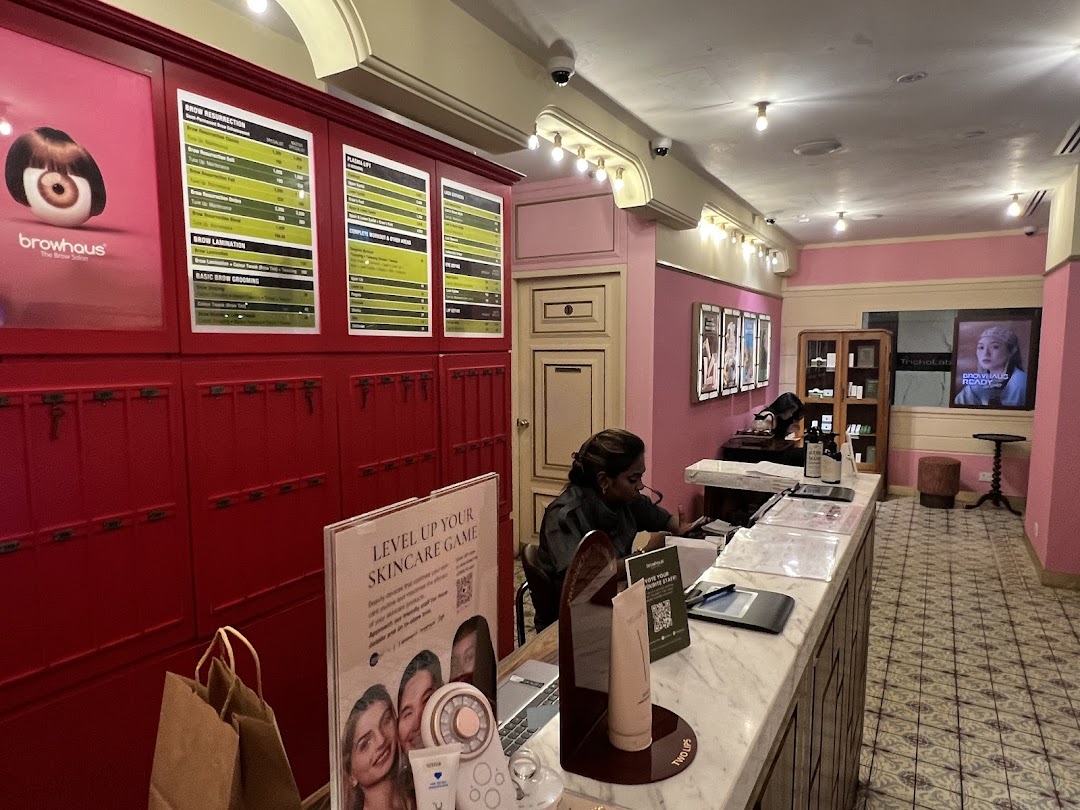 An interior view of Strip Co-Ed, featuring a reception desk, staff, and service menus for beauty treatments.