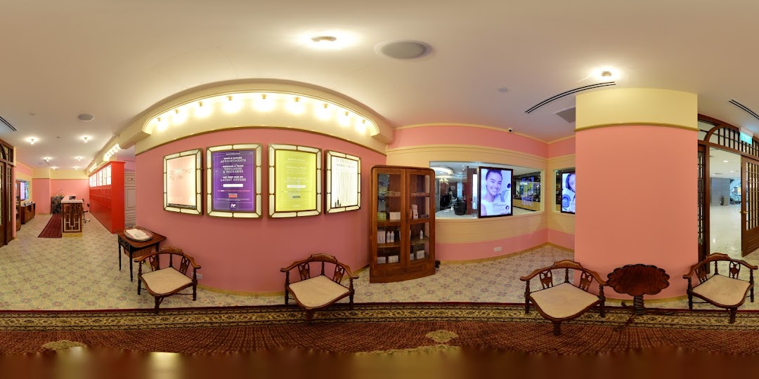 A vibrant pink-themed interior of Strip Co-Ed Plaza Singapura, featuring a waiting area, reception, and product displays.
