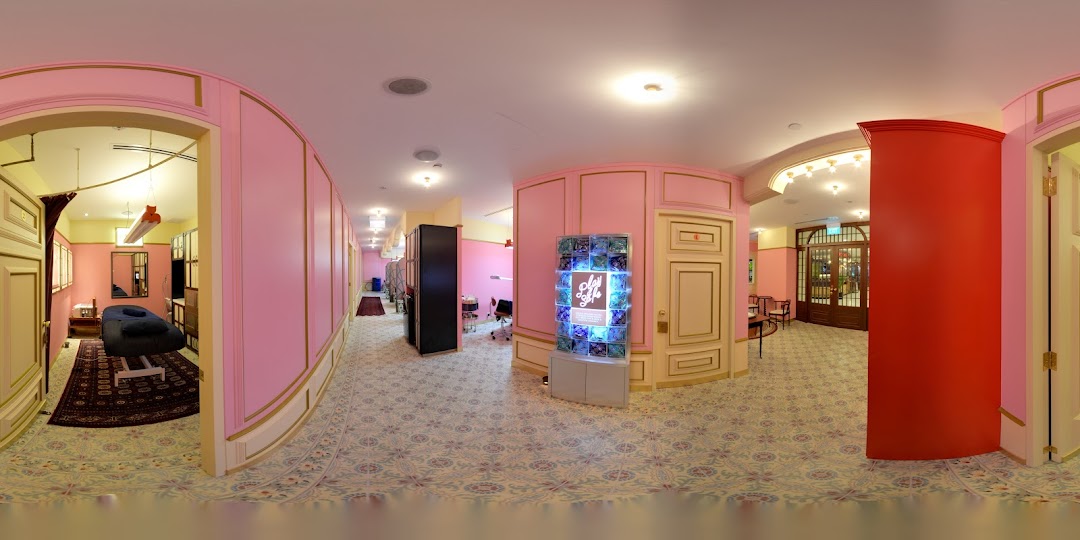 A vibrant pink and gold interior hallway leading to treatment rooms and a reception area.