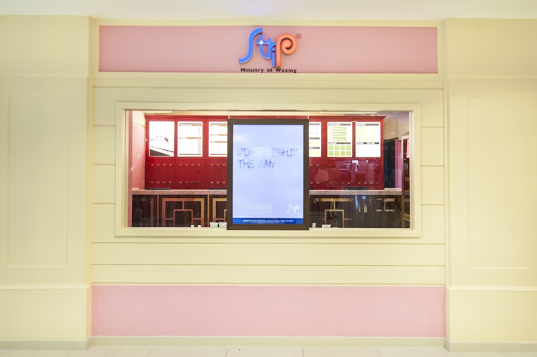 The storefront of Strip Co-Ed Plaza Singapura, a waxing salon, featuring its logo and a promotional display.