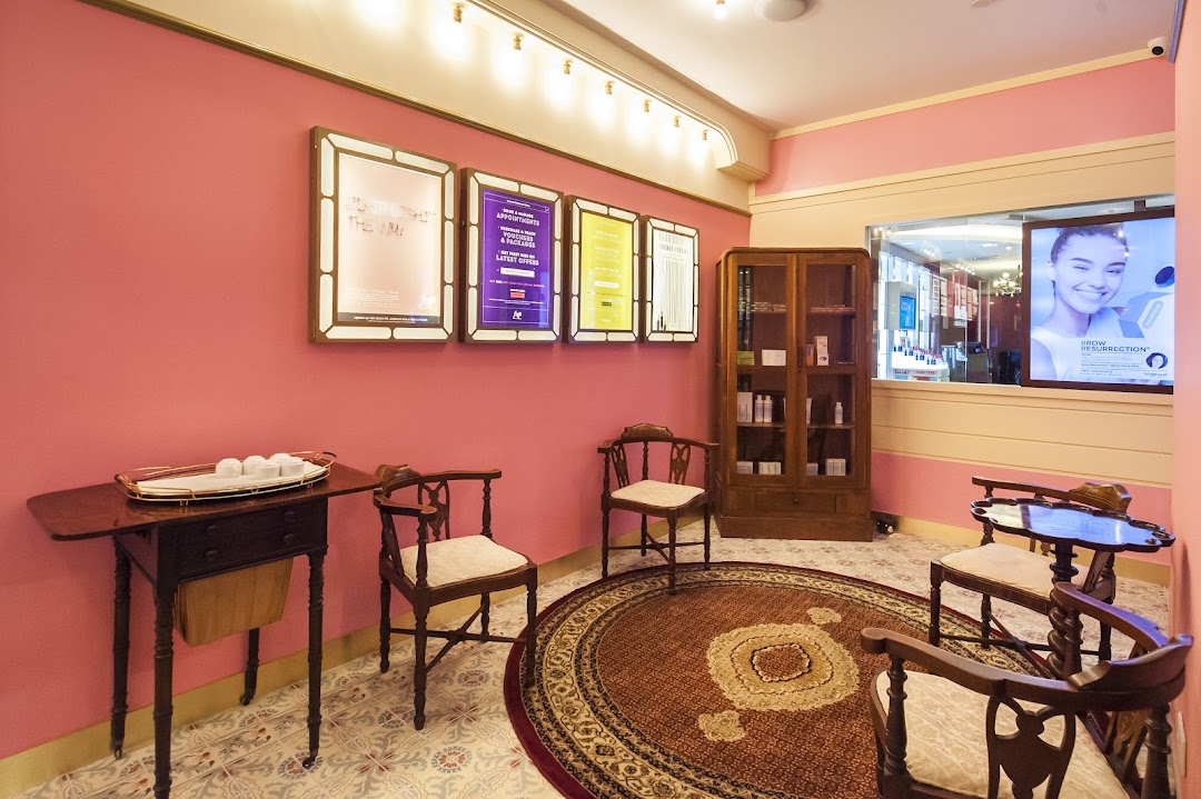 A stylish pink-walled waiting area with vintage furniture and promotional displays.