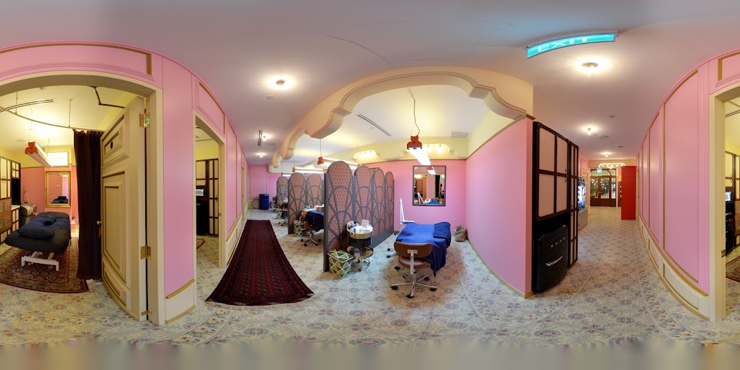 Interior view of a beauty salon with multiple treatment areas, pink walls, and patterned floors.