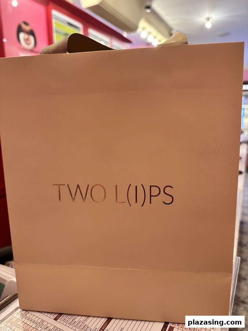A light pink shopping bag with 'TWO L(I)PS' branding, likely from a beauty or body care shop.