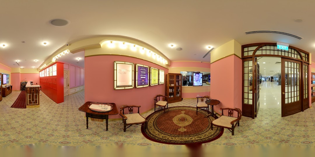 A panoramic view of Strip Co-Ed's elegant pink and gold interior with a waiting area and reception.