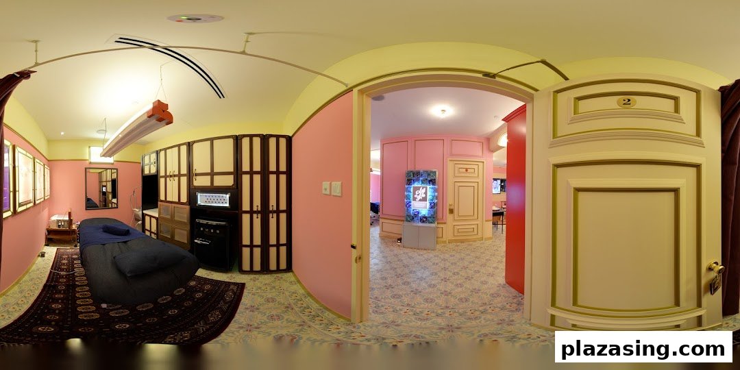 An interior view of a treatment room with a bed and a glimpse into a pink-walled hallway.