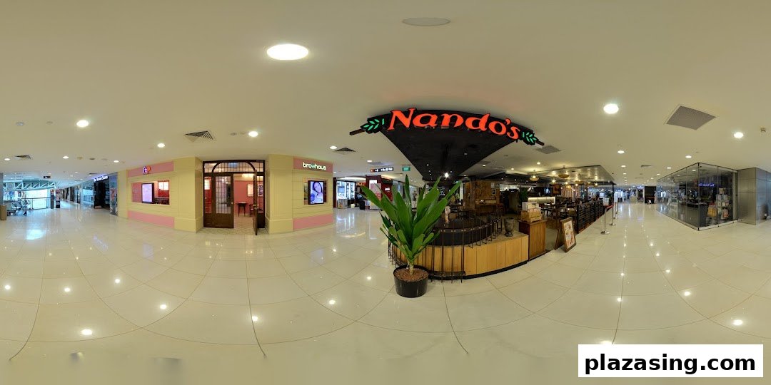 A brightly lit shopping mall corridor featuring various retail outlets and dining options like Nando's.