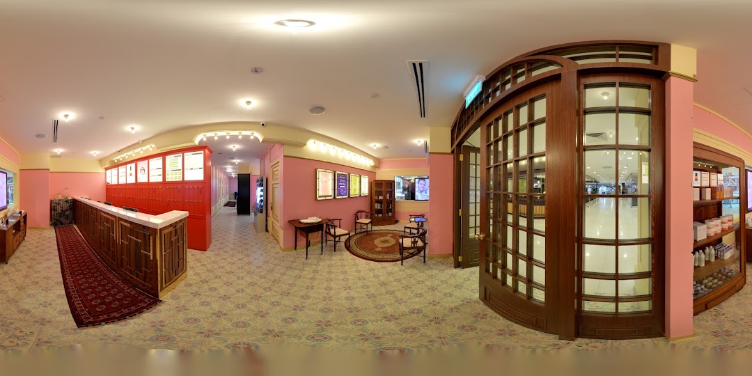 A vibrant pink-themed interior of Strip Co-Ed, featuring a reception desk, waiting area, and product displays.
