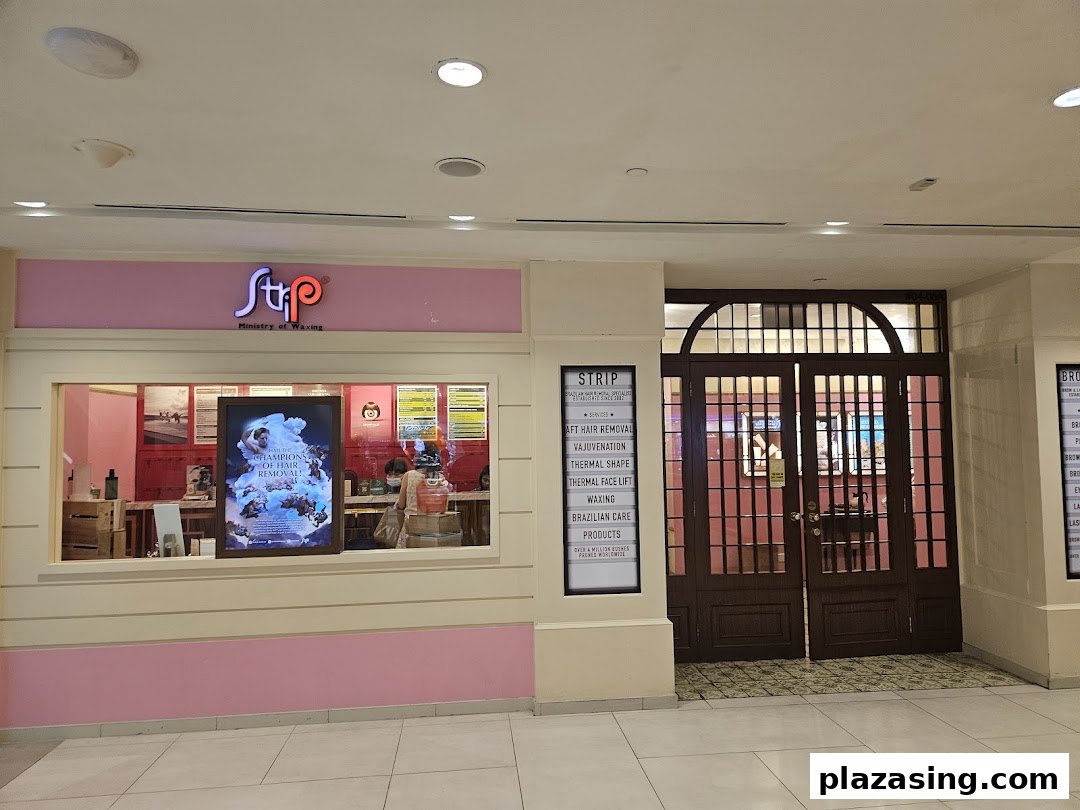 The pink facade of Strip: Ministry of Waxing, showcasing its entrance and a list of specialized services.