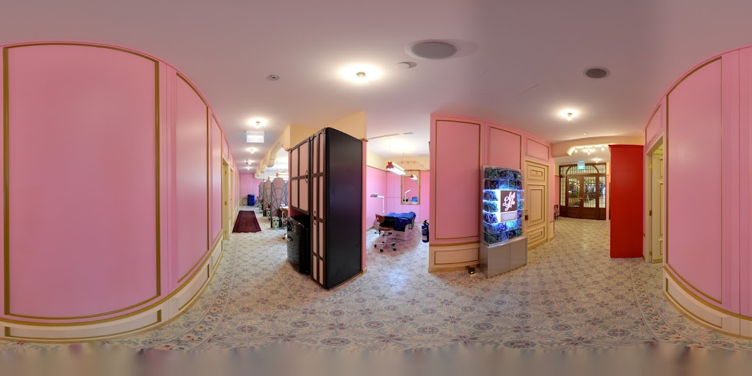 A vibrant pink and gold interior of a beauty salon with patterned floors and treatment areas.