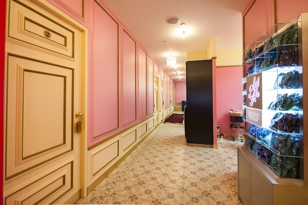 A vibrant pink and gold hallway with patterned flooring and a product display at Strip Co-Ed.