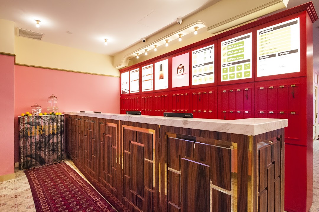 A vibrant reception area with a stylish wooden counter, marble top, and red wall panels displaying services.