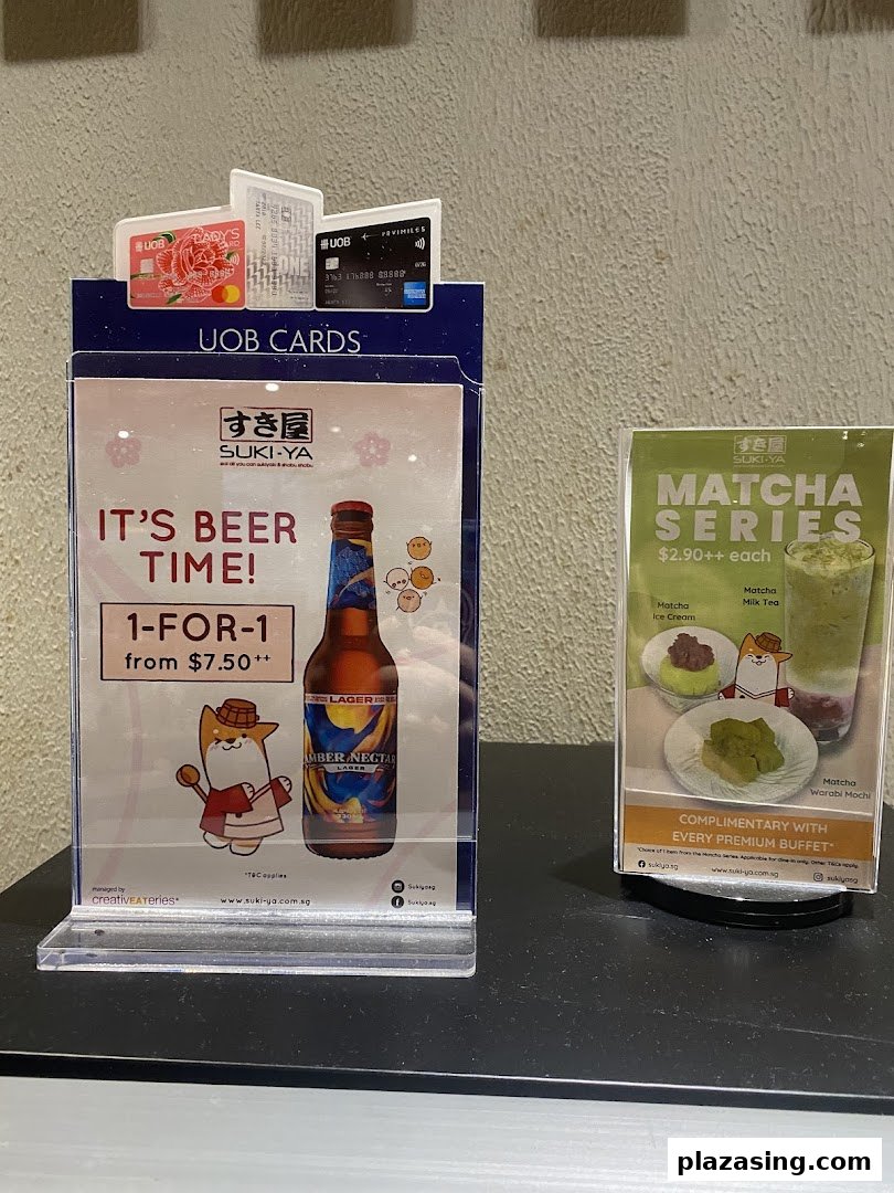 Two promotional displays from Suki-Ya featuring a 1-for-1 beer offer and a Matcha Series with prices.