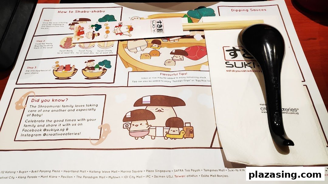 A Suki-Ya placemat detailing shabu-shabu cooking steps and tips, with chopsticks and a spoon.
