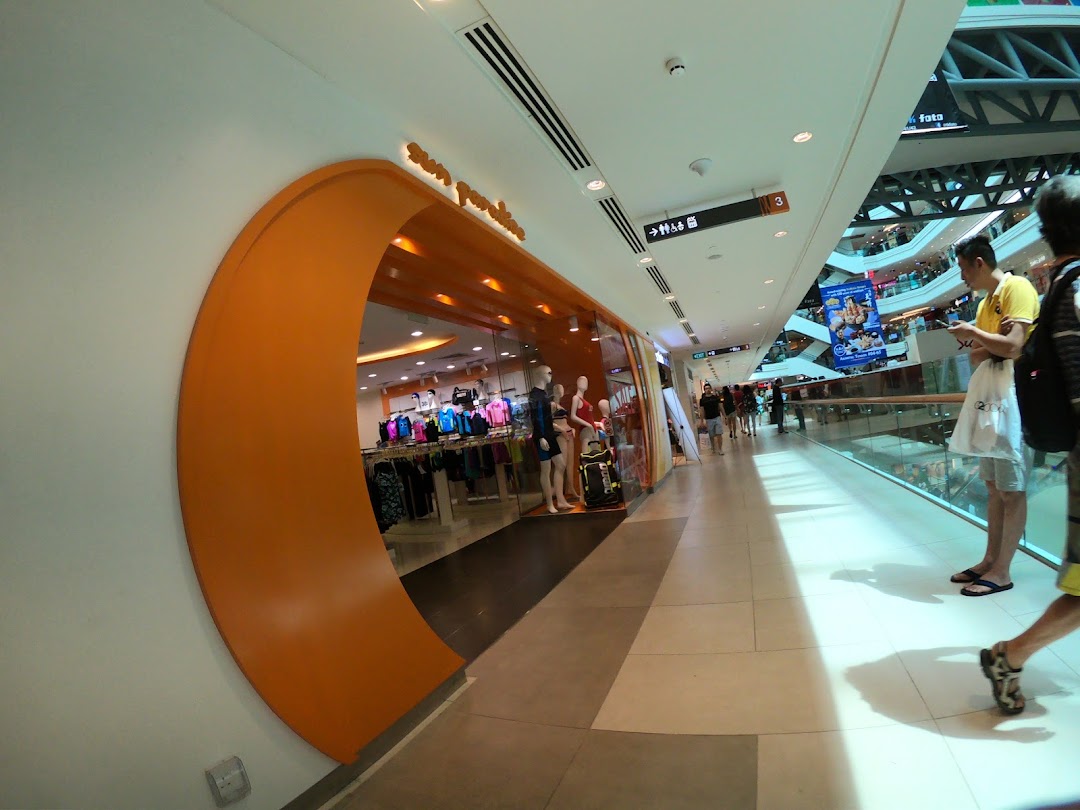 The vibrant orange entrance of Sun Paradise, showcasing swimwear and activewear within a bustling mall corridor.