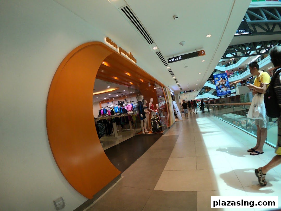 The vibrant orange entrance of Sun Paradise, showcasing swimwear and activewear within a bustling mall corridor.
