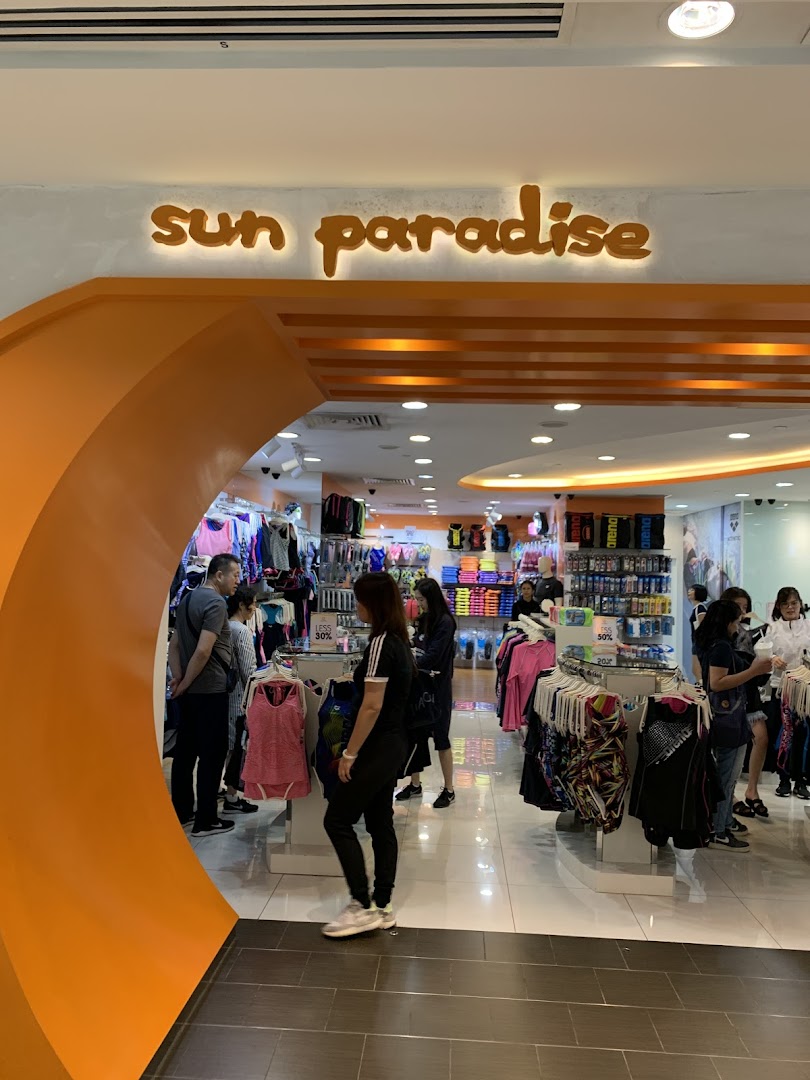 The vibrant orange entrance of Sun Paradise, a retail store offering activewear and swimwear, with customers browsing inside.