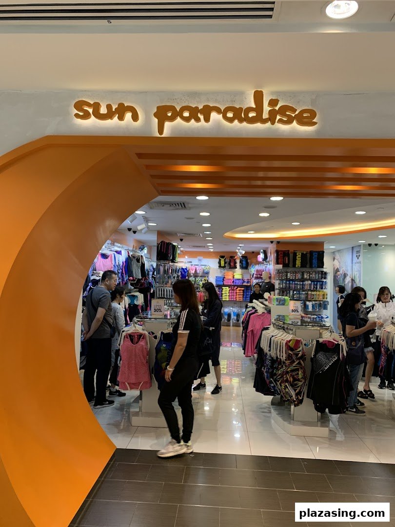 The vibrant orange entrance of Sun Paradise, a retail store offering activewear and swimwear, with customers browsing inside.