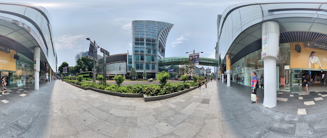 A panoramic view of a vibrant urban street with modern buildings, pedestrians, and retail shopfronts.