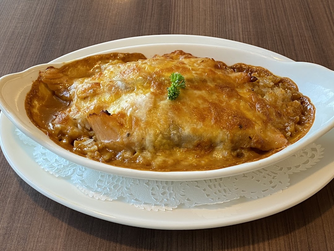 A close-up of a delicious baked rice or pasta dish with melted cheese, served in a white oval dish.