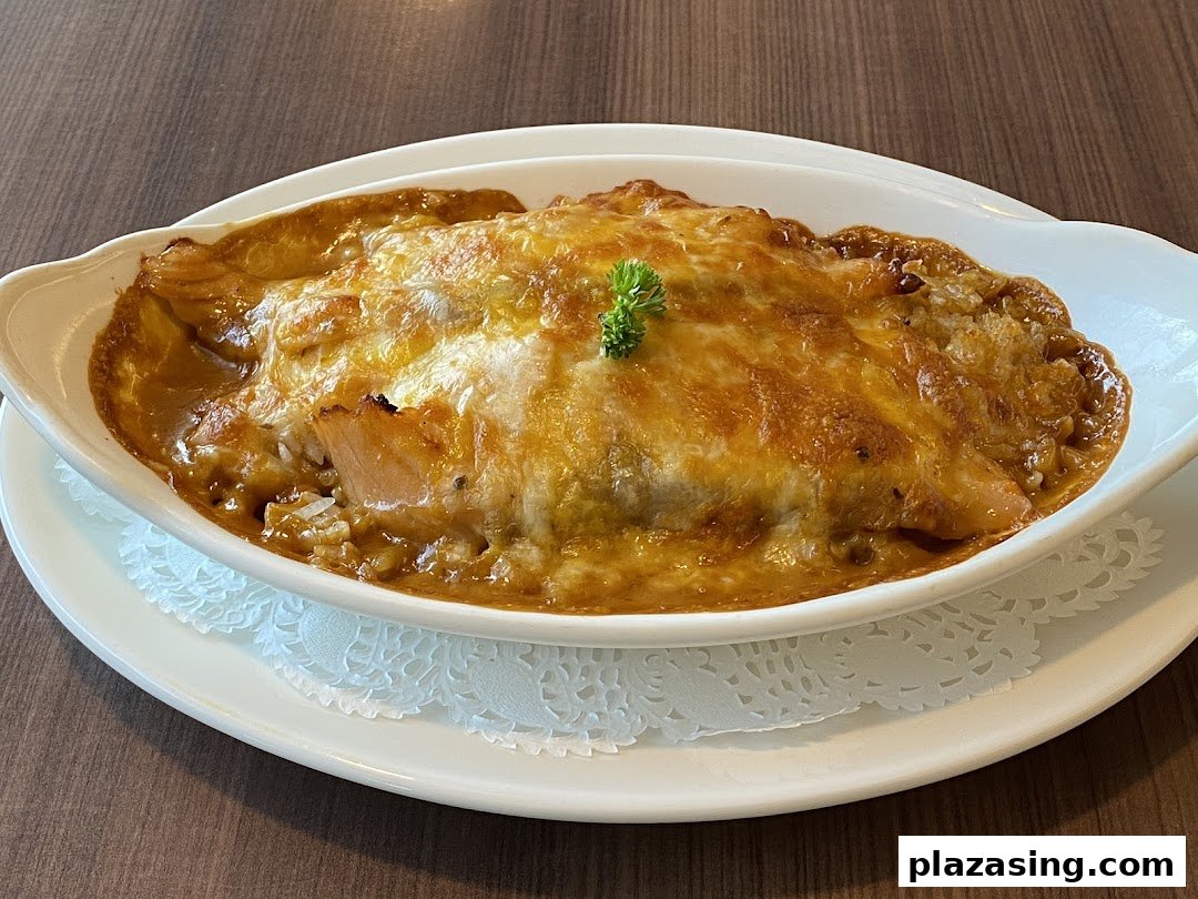 A close-up of a delicious baked rice or pasta dish with melted cheese, served in a white oval dish.