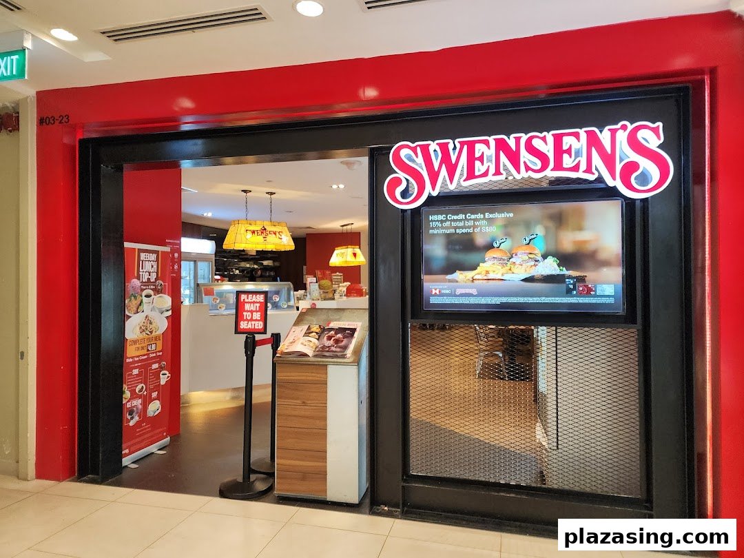 The vibrant red and black entrance of Swensen's at Plaza Singapura, featuring a digital display and a 'wait to be seated' sign.