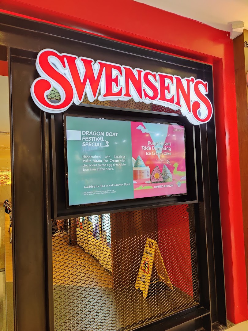The illuminated entrance of Swensen's at Plaza Singapura, featuring its prominent sign and a digital promotional display.