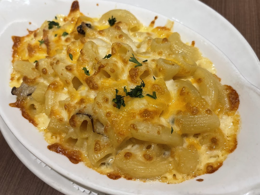 A close-up of a baked macaroni and cheese dish with melted golden cheese and parsley garnish.