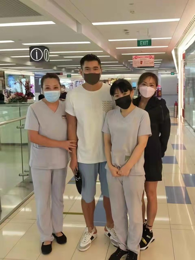 Four individuals, including three staff members in uniforms and a male customer, all wearing masks, in a mall corridor.