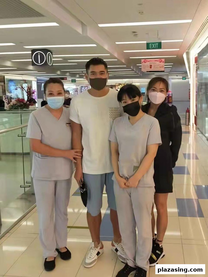 Four individuals, including three staff members in uniforms and a male customer, all wearing masks, in a mall corridor.