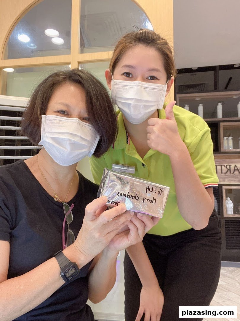 A happy customer and staff member in masks holding a gift, showcasing friendly service.