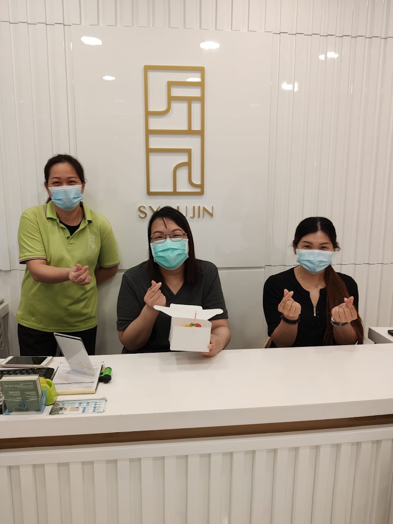 Three friendly Syoujin staff members, wearing masks, welcome customers from behind their clean, modern counter.