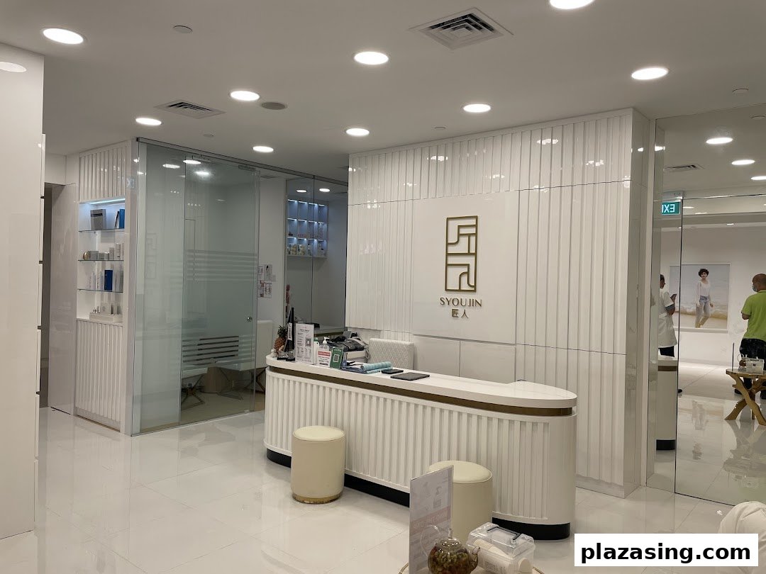 A bright, modern reception area with a white counter and the Syoujin logo.