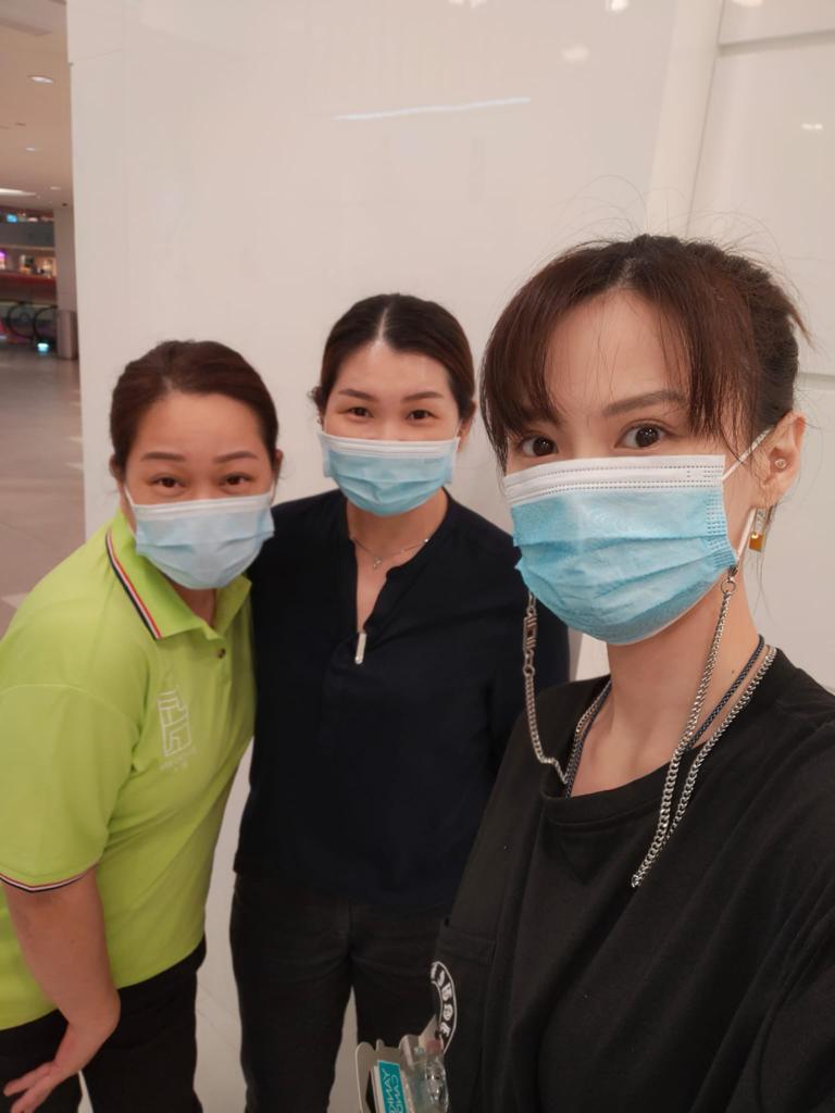 Three individuals, including a staff member in uniform, wearing masks and posing for a photo.