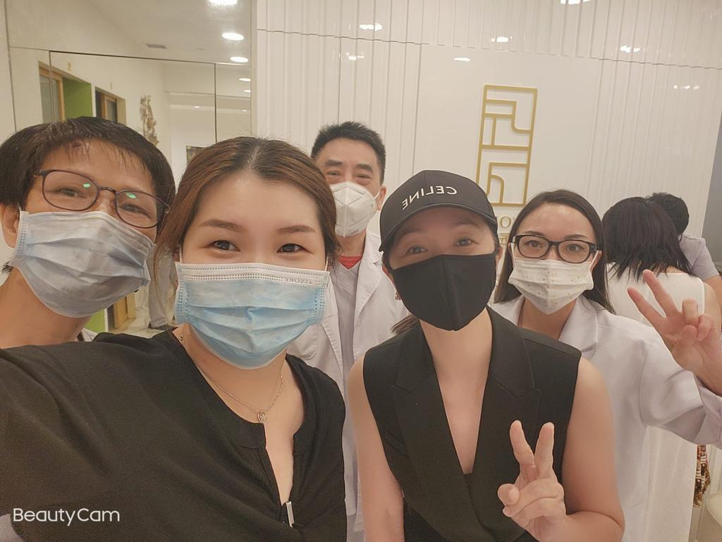 A group of masked staff and customers smiling for a selfie inside Syoujin 匠人.