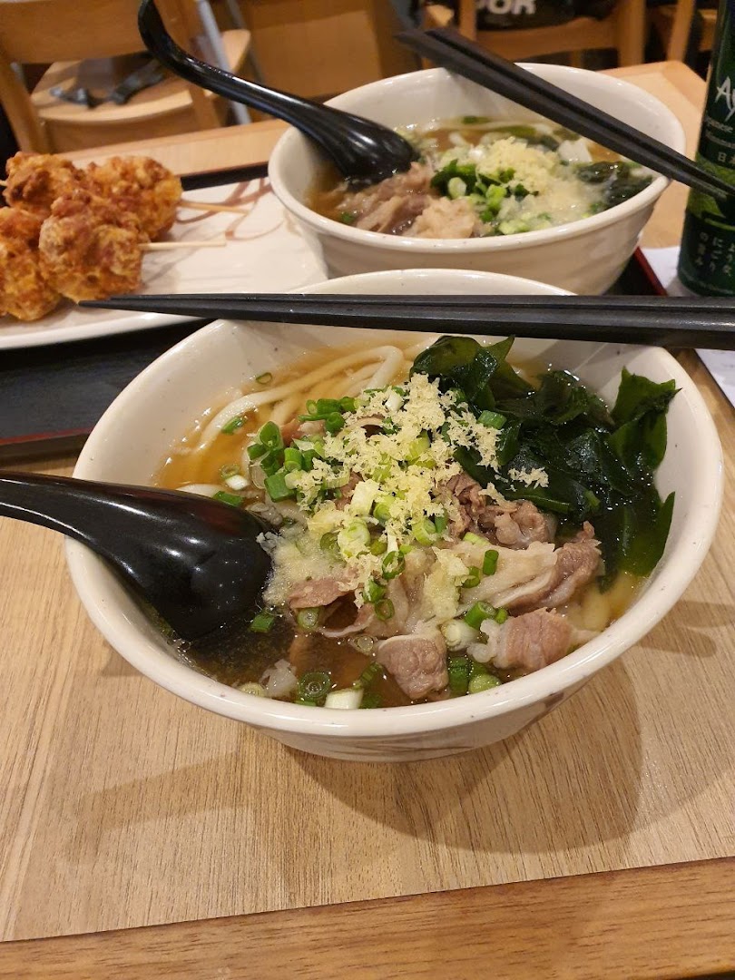 Two bowls of delicious udon noodles with toppings and a side of crispy tempura.
