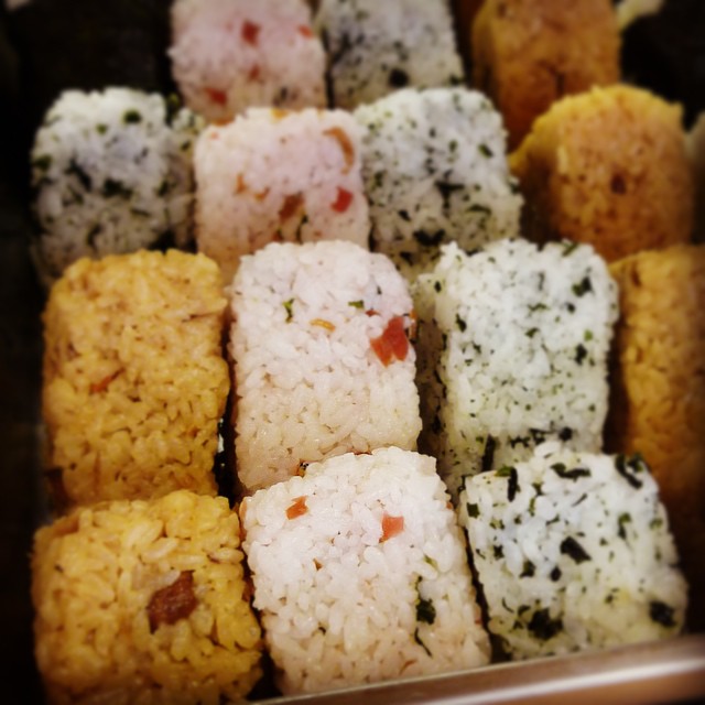 A close-up of various Japanese rice balls with different toppings and flavors.