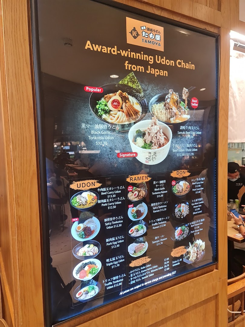 A brightly lit menu board showcasing a variety of Japanese udon, ramen, and donburi dishes with prices.
