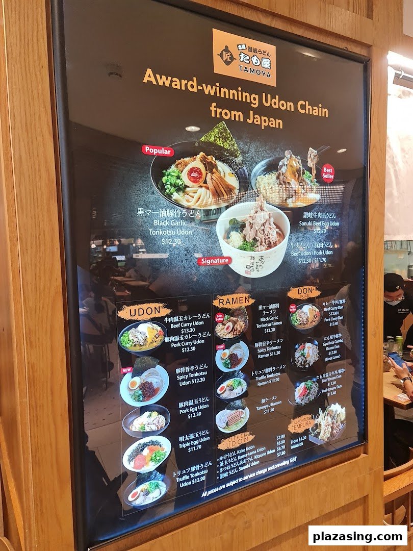 A brightly lit menu board showcasing a variety of Japanese udon, ramen, and donburi dishes with prices.