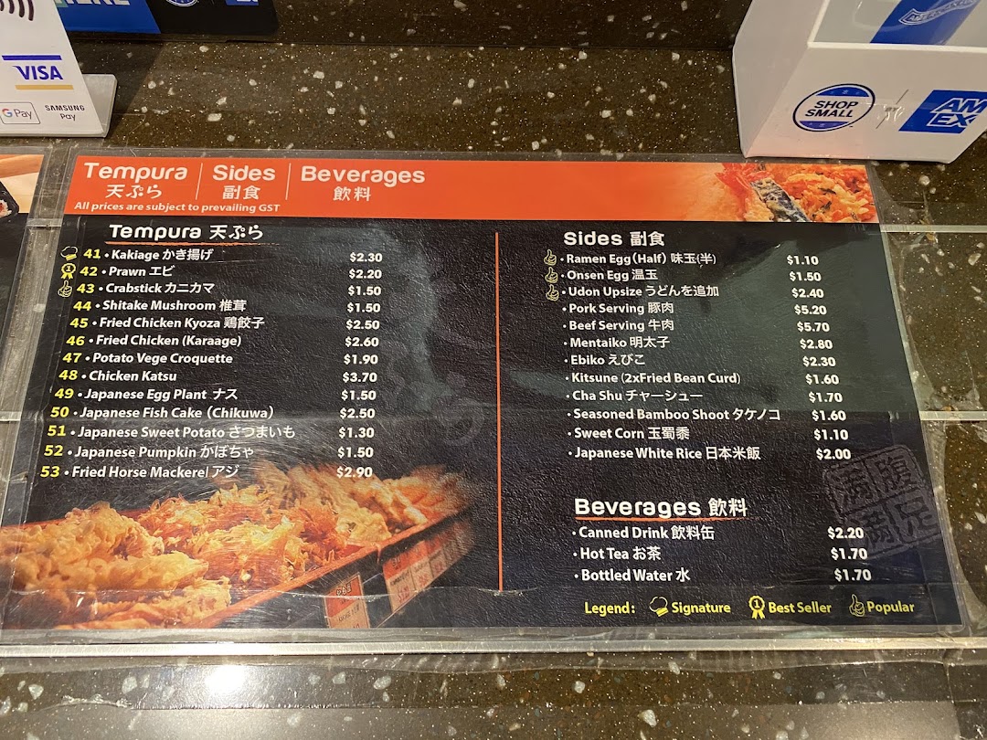A detailed menu board displaying a variety of Japanese tempura, side dishes, and beverages with prices.