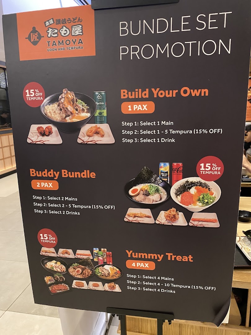 A promotional display board for Tamoya Udon & Tempura, showcasing various bundle set promotions.
