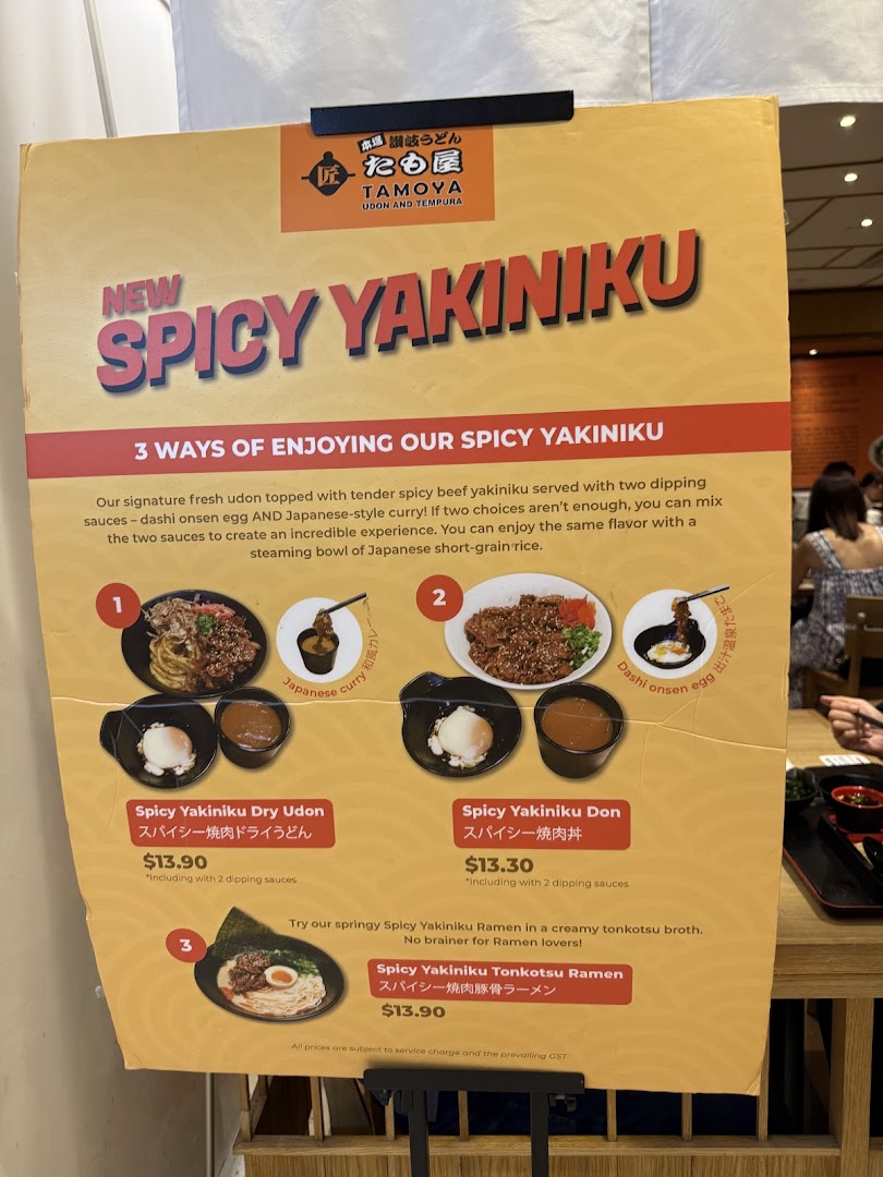 A promotional menu board showcasing Tamoya Udon Tempura's new 'Spicy Yakiniku' dishes with prices and descriptions.