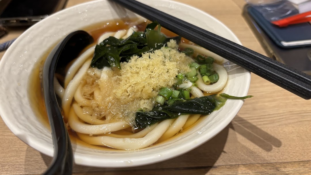 A close-up of a delicious bowl of udon noodles with toppings and broth, ready to be enjoyed.
