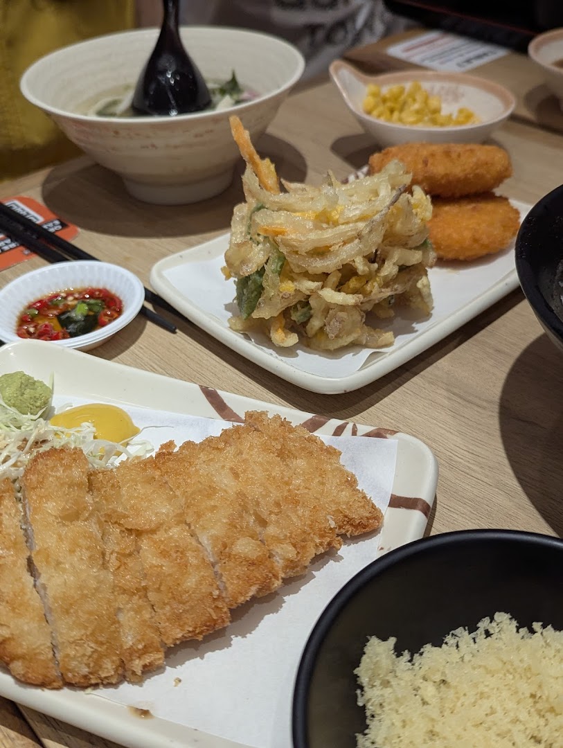 A table laden with delicious Japanese dishes including udon, crispy tempura, and golden tonkatsu.