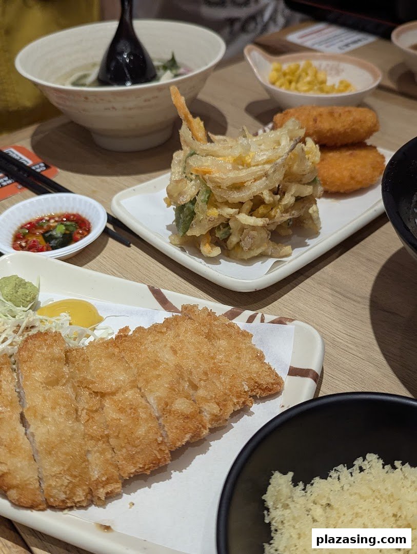 A table laden with delicious Japanese dishes including udon, crispy tempura, and golden tonkatsu.