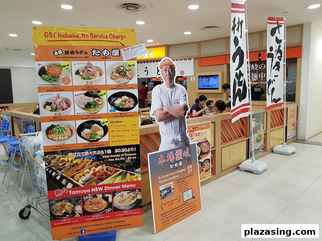 A promotional display for Tamoya Udon & Tempura, featuring a menu banner, chef standee, and shop entrance.