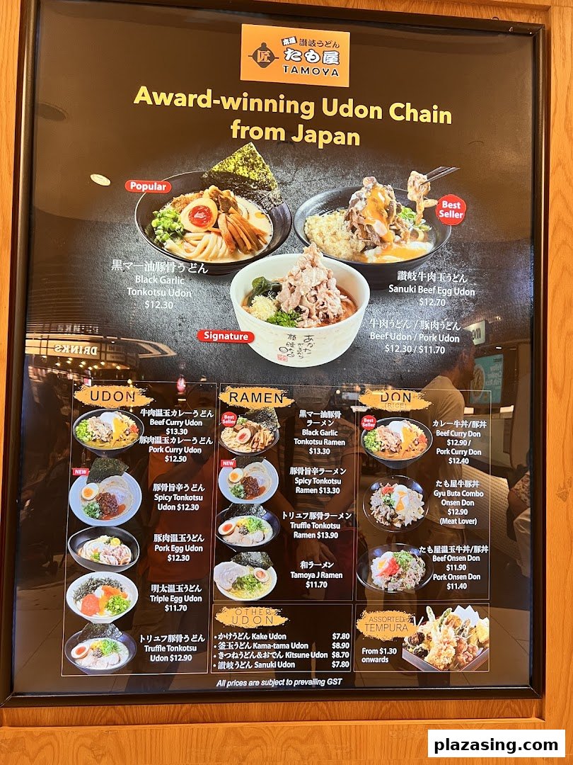 A large menu board for Tamoya Udon, showcasing various Japanese udon, ramen, donburi, and tempura dishes with prices.