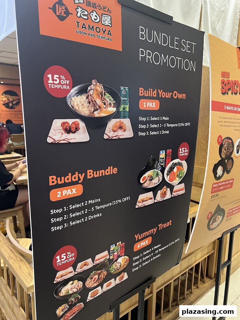 A promotional stand for Tamoya Udon & Tempura, showcasing various bundle set promotions and a new spicy udon dish.